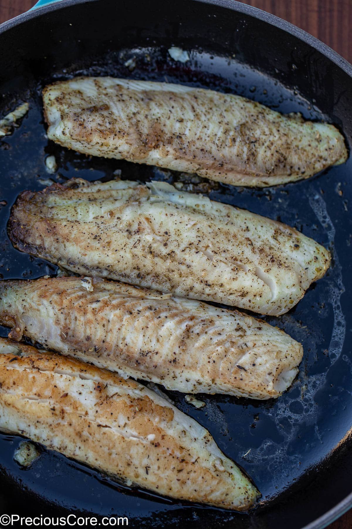 Seasoned and cooked fish in pan.