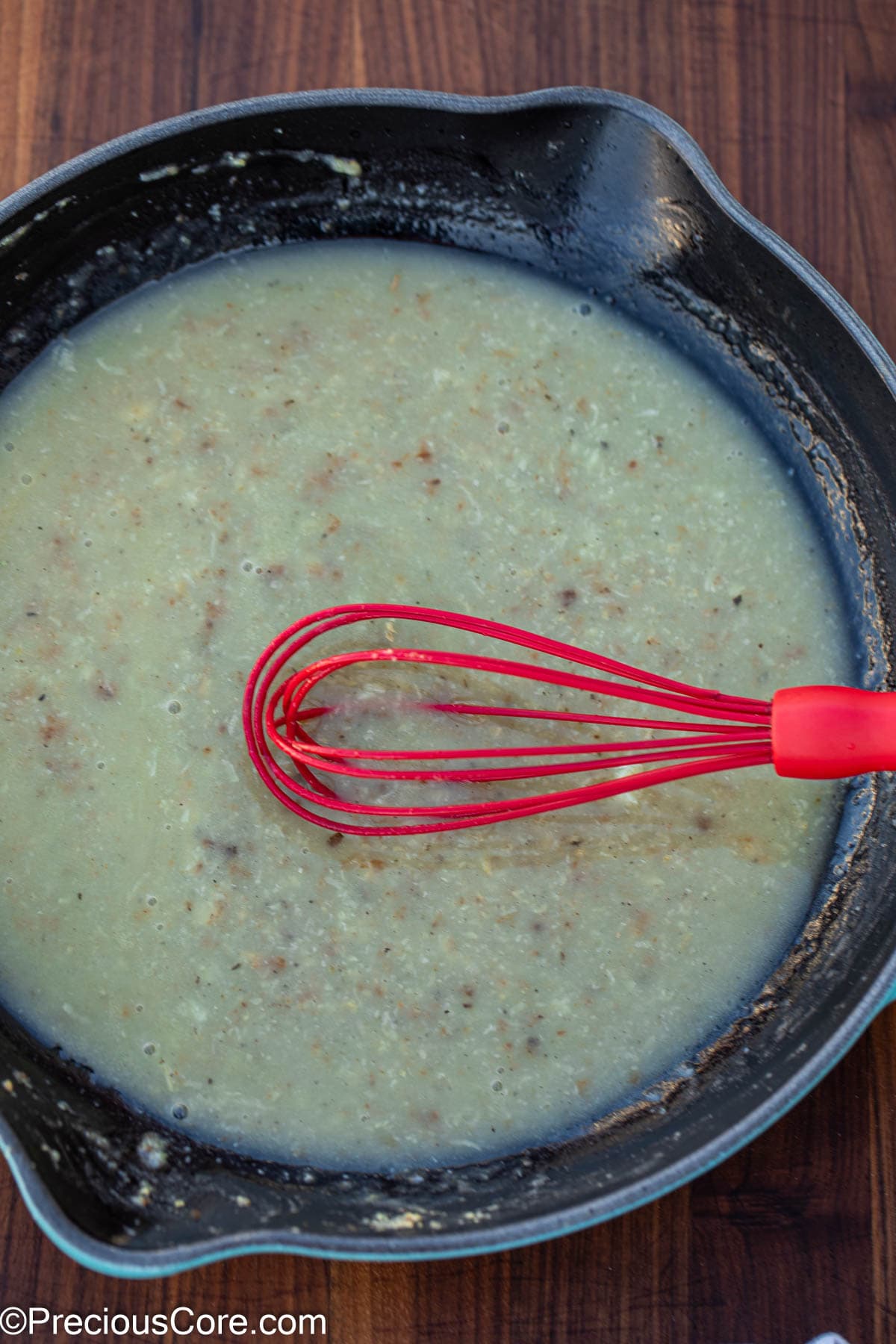 Mixing white sauce with a whisk.