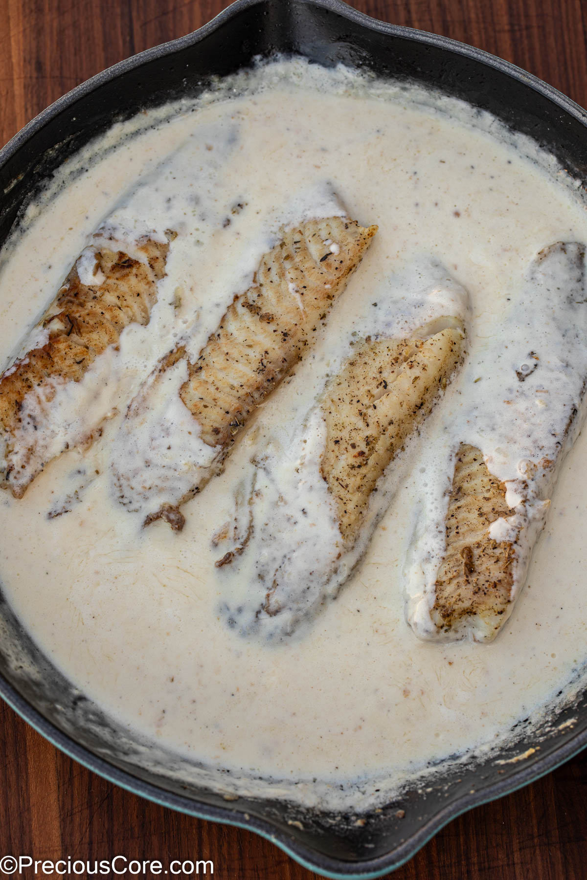 Fish cooking in white sauce.
