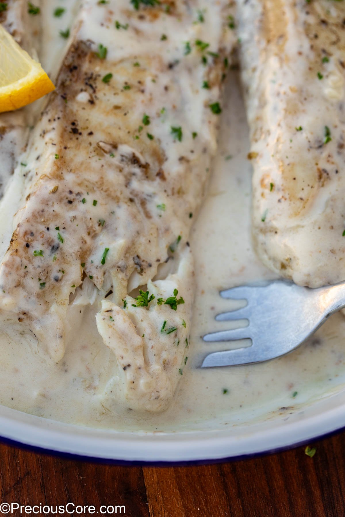 Dipping fork into fish in white sauce.