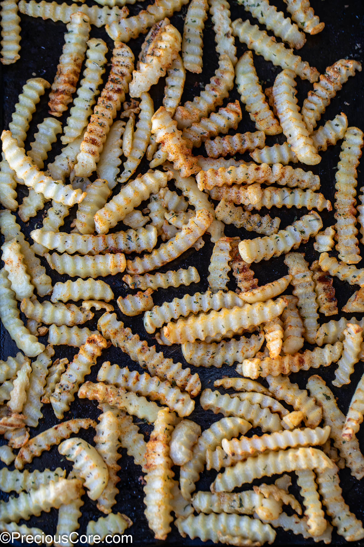 Seasoned crinkle-cut fries on a sheet pan.