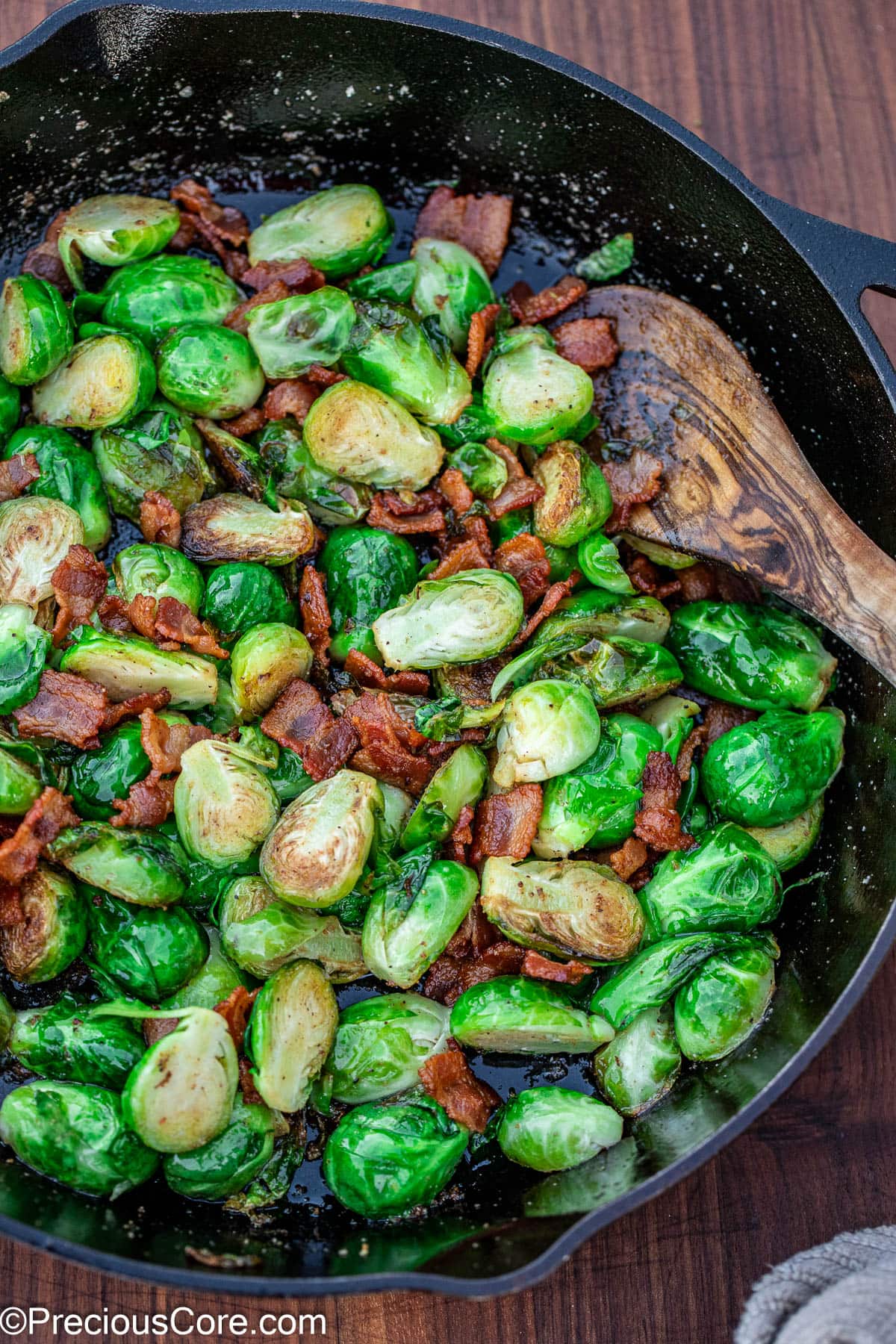 Pan-fried Brussels sprouts with bacon in a black skillet.