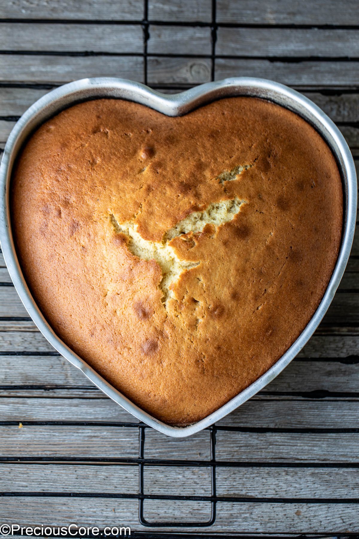 Heart shaped plain cake on a cooling rack.