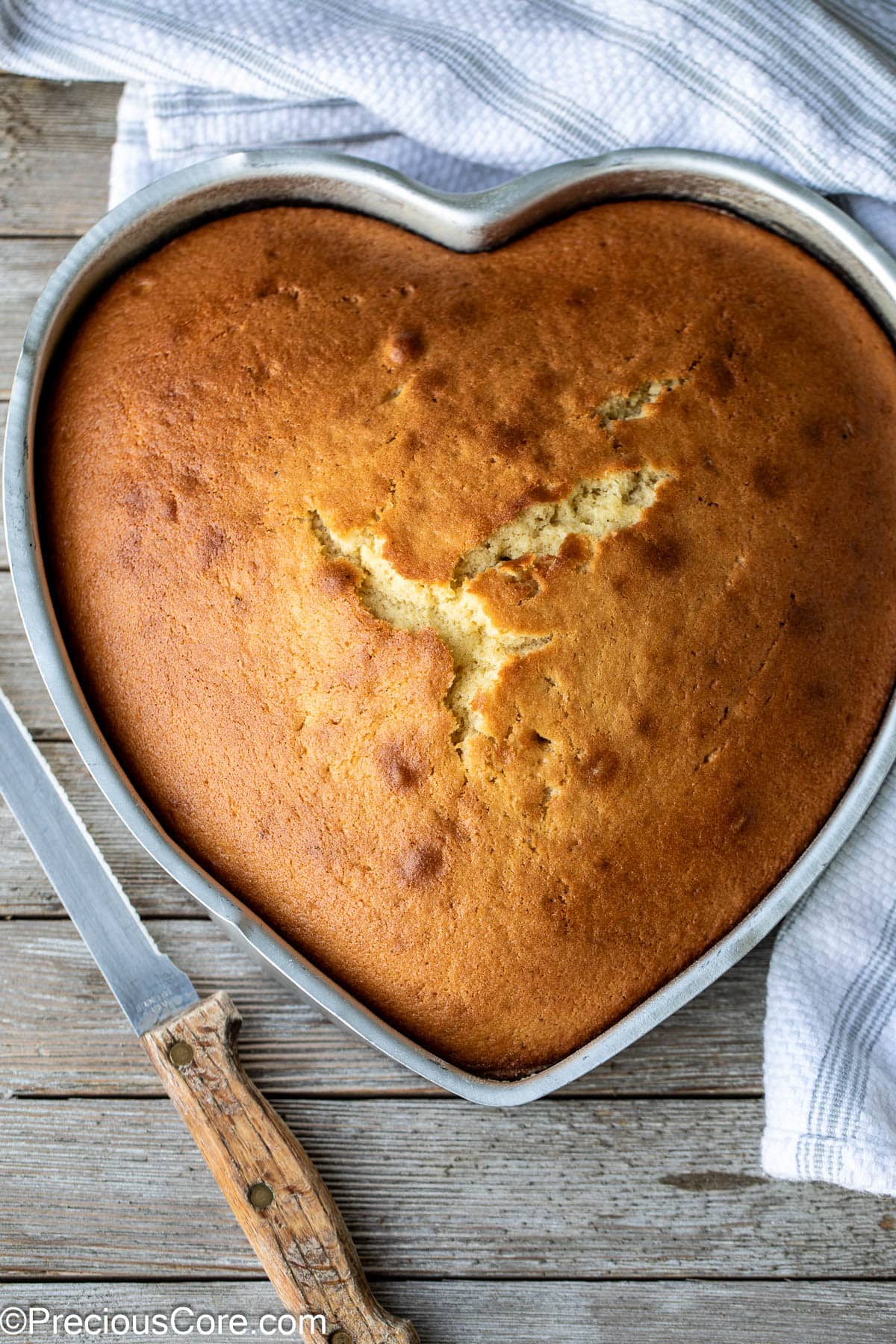 Plain cake in a heart-shaped pan with a knife on the side.