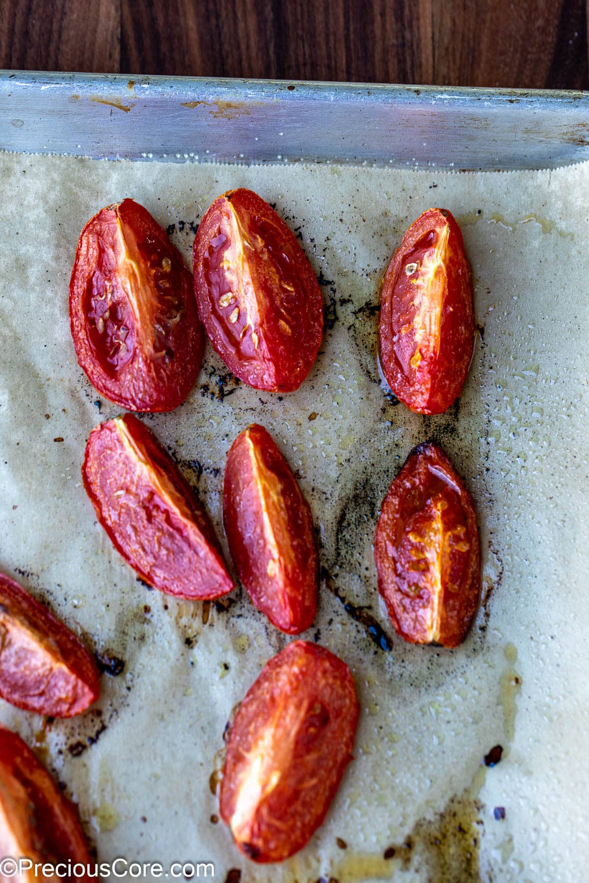Roasted tomatoes on a baking sheet lined with parchment paper.