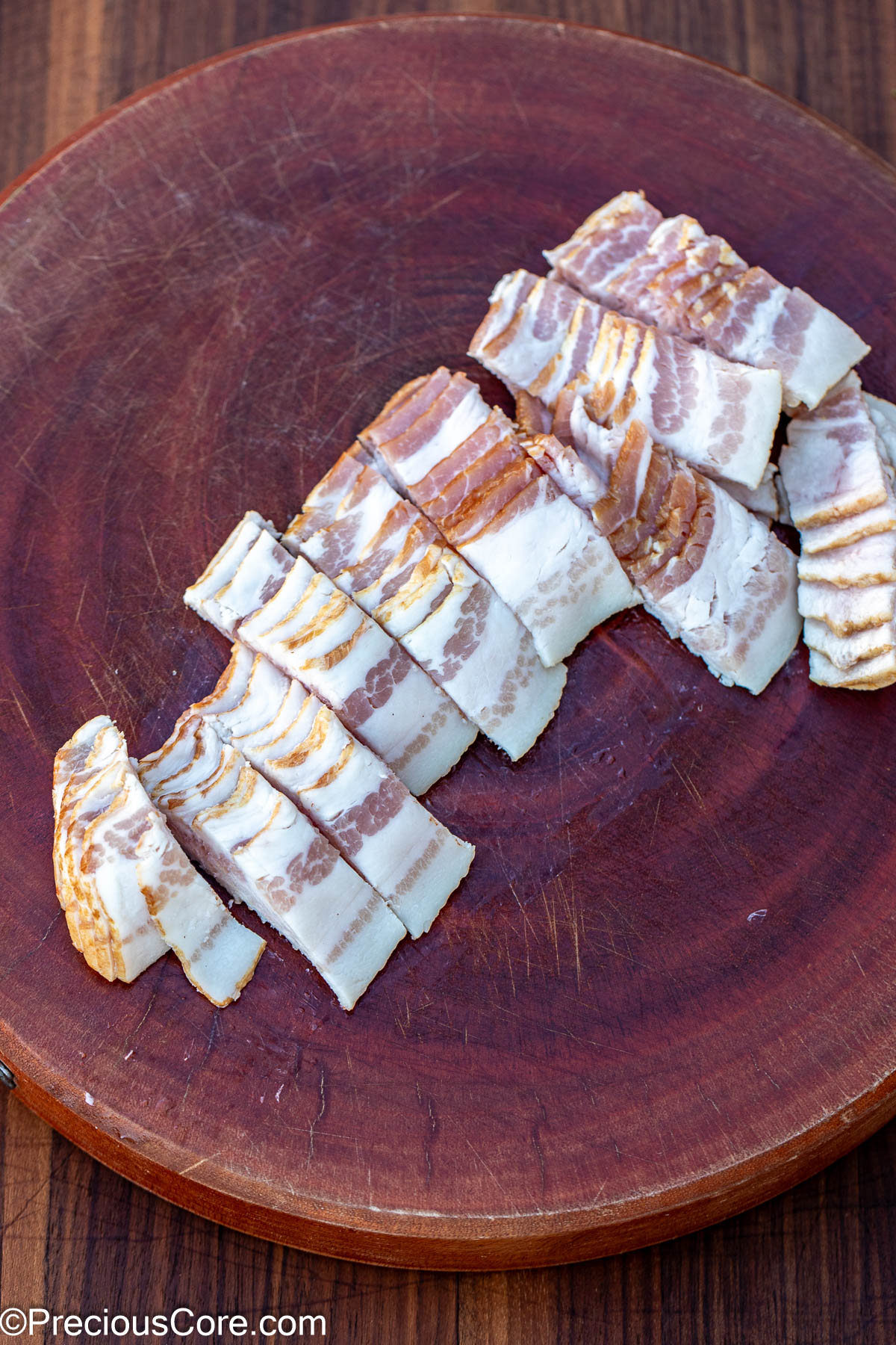 Sliced bacon on a round chopping board.