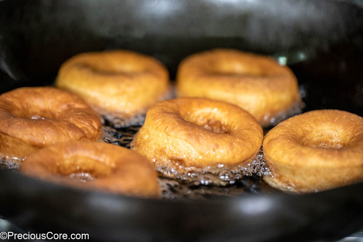 Golden brown donuts frying in oil.
