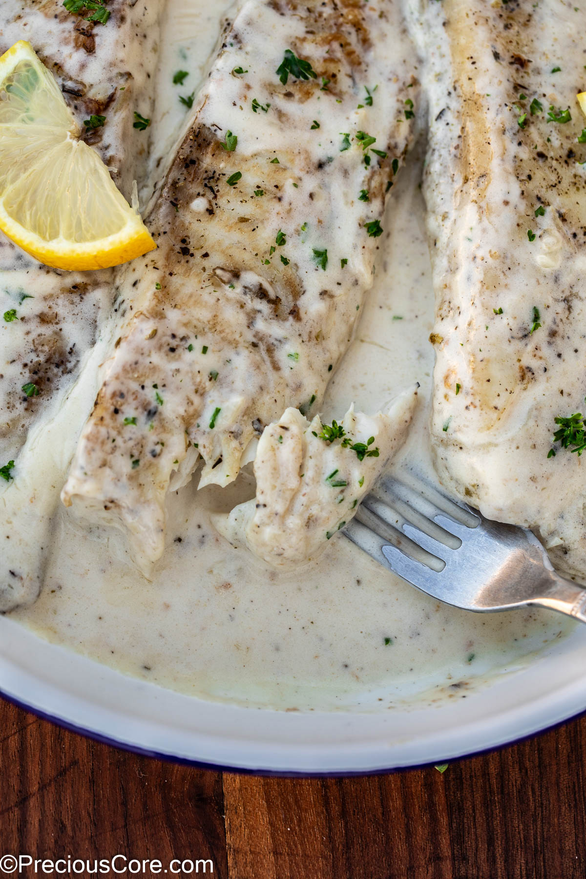 Fork showing flakiness of cooked fish.