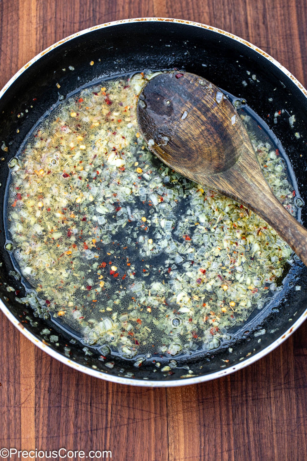 White wine sauce with garlic and shallots in a skillet.