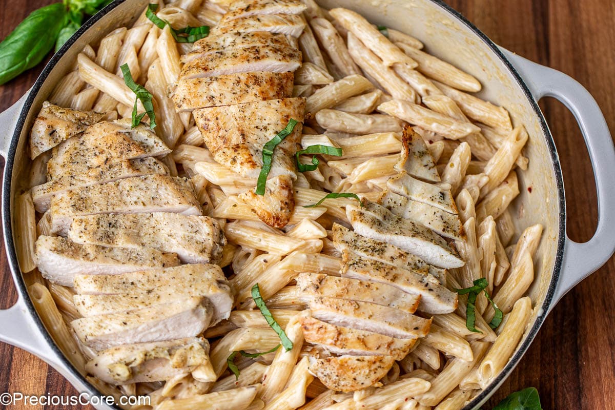 Landscape image of garlic parmesan creamy pasta topped with chicken.