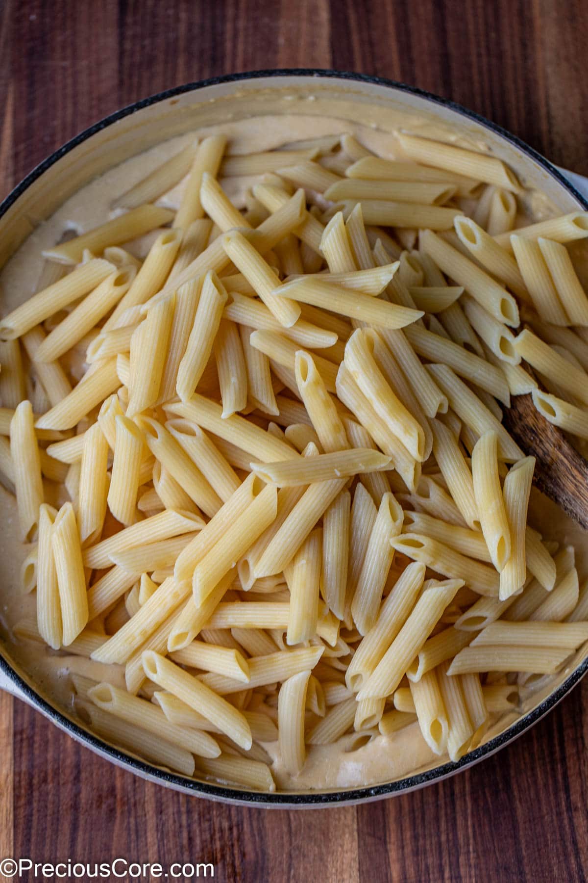 Cooked pasta in a pot of white creamy sauce.