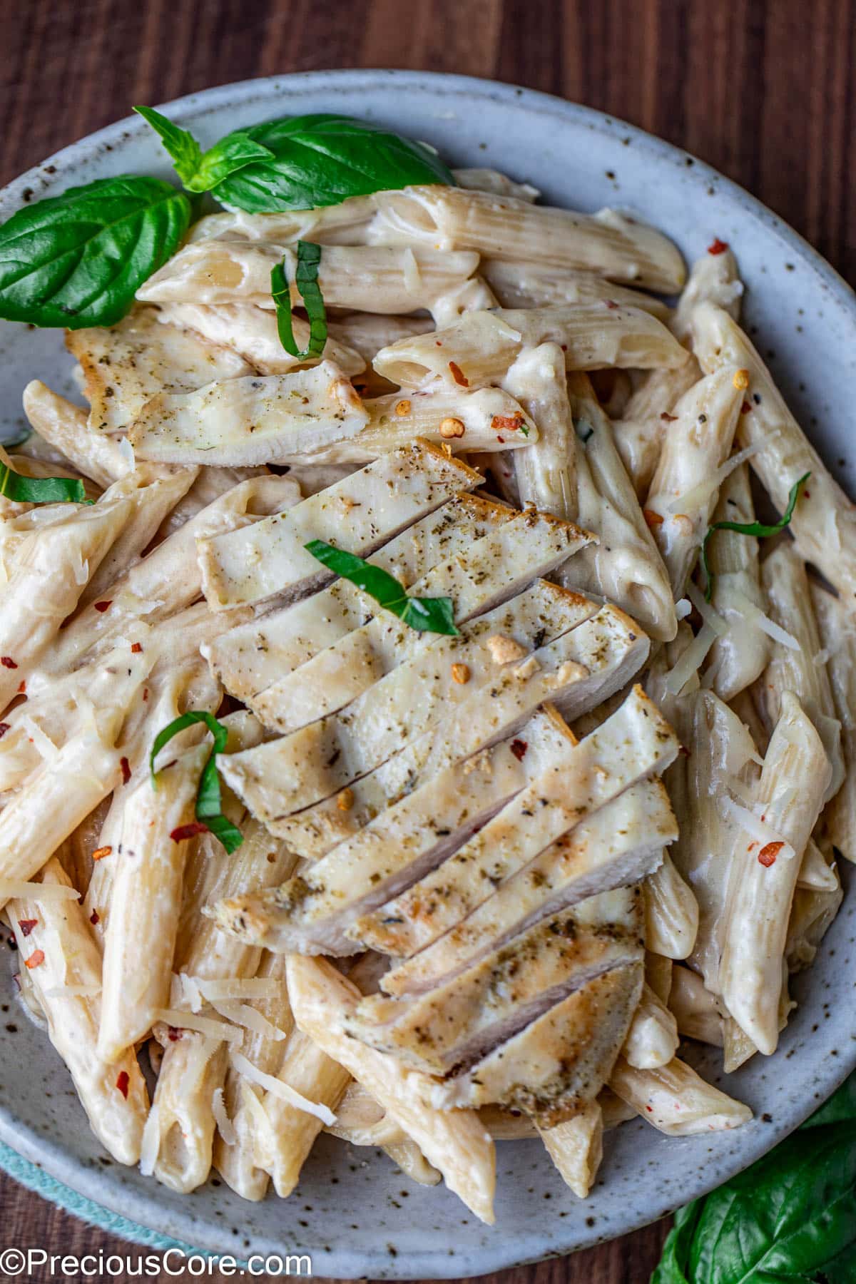 A bowl of creamy pasta topped with sliced chicken breast.