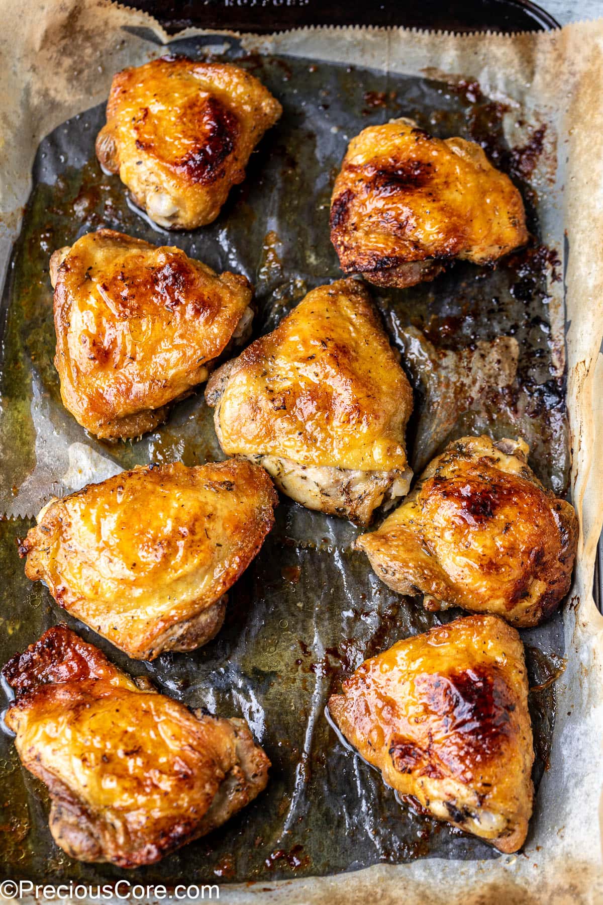 Broiled mayonnaise chicken thighs on a baking sheet lined with parchment paper.