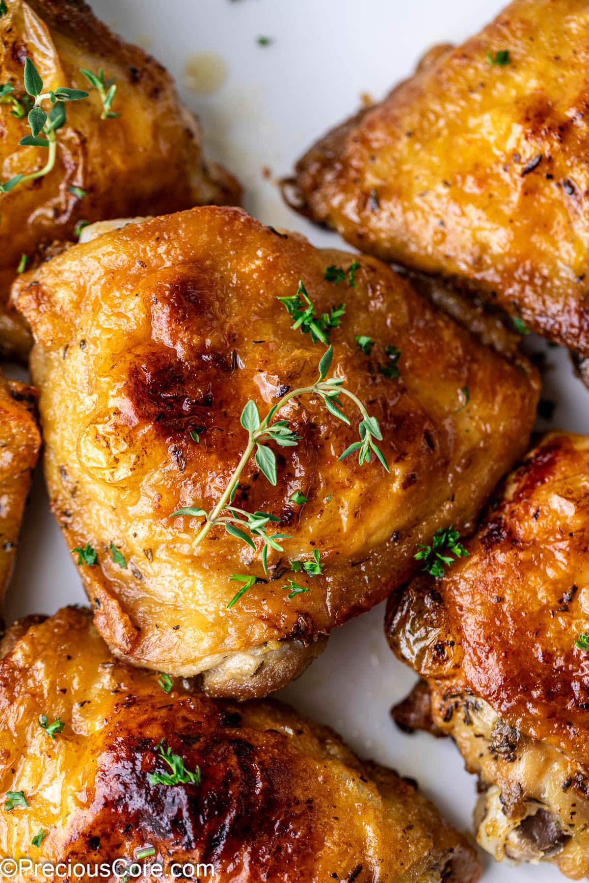 Close up on a golden brown chicken thigh, surrounded by other chicken thighs.
