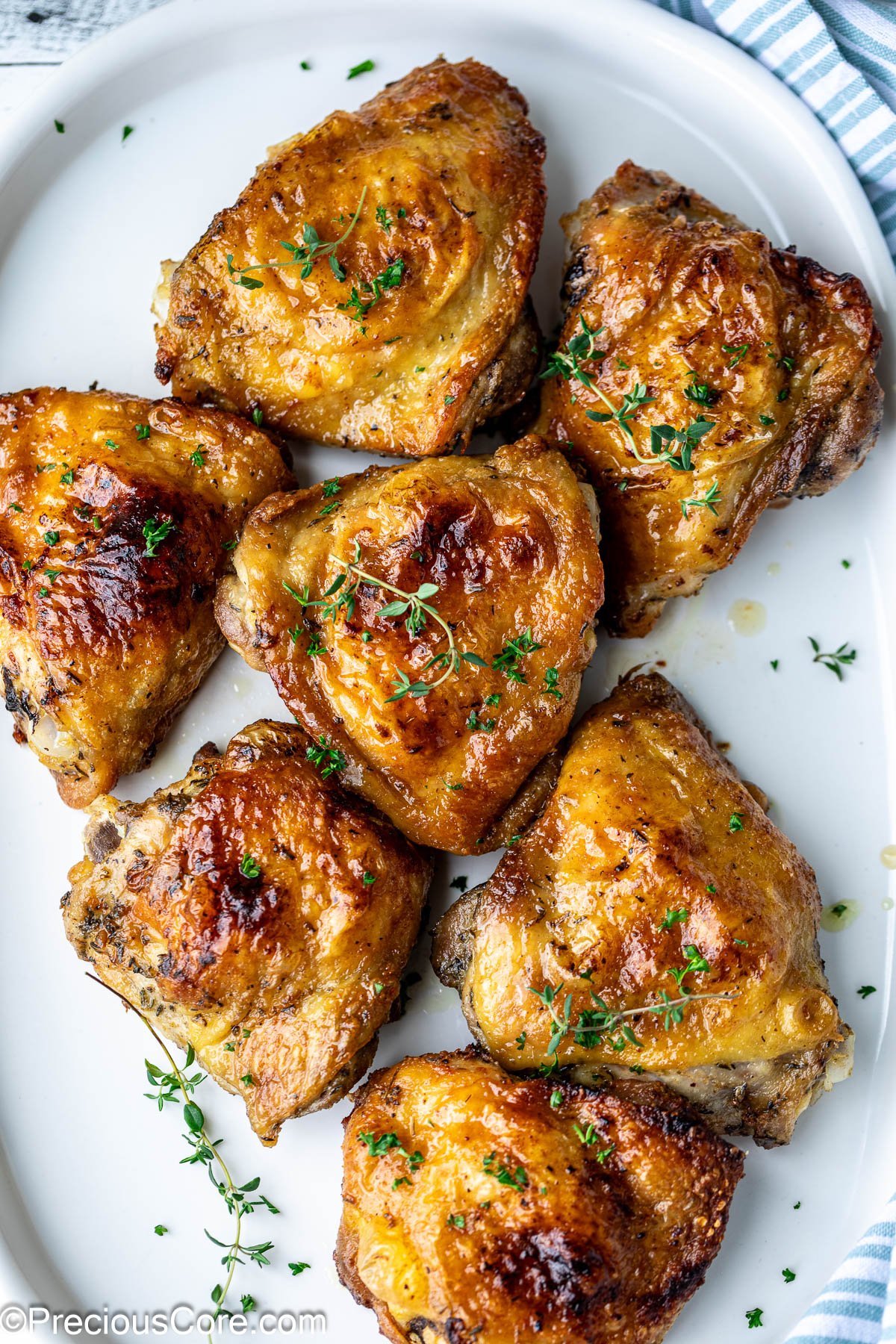 Mayonnaise chicken thighs garnished with fresh thyme on a white platter.