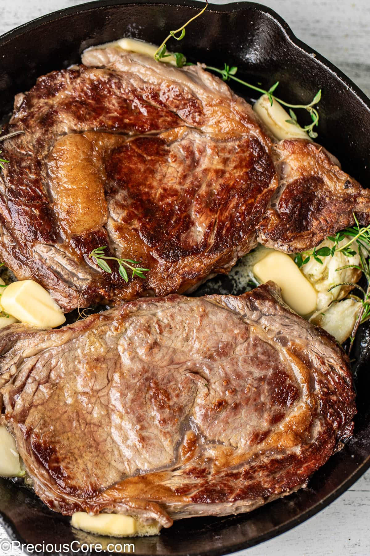 2 ribeye steaks in a cast iron skillet.