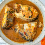 A bowl with three steaks of catfish in pepper soup.