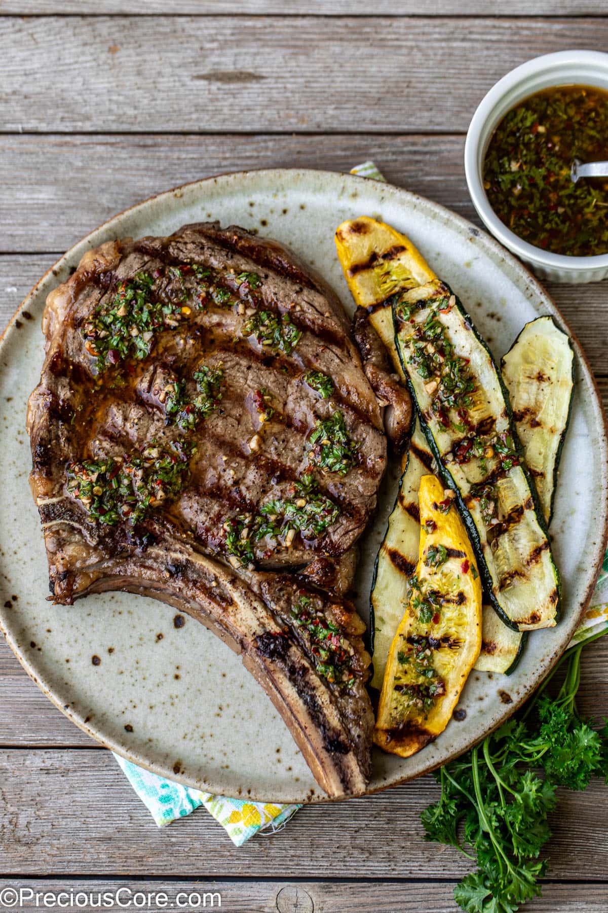 Overhead shot of steak topped with chimichurri and served with zucchini.