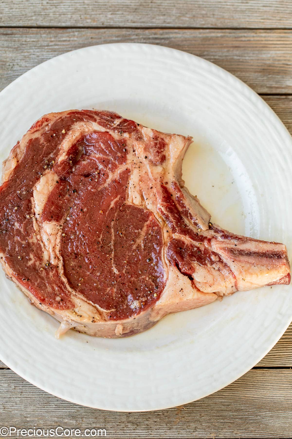 Bone-in steak seasoned with salt and pepper.