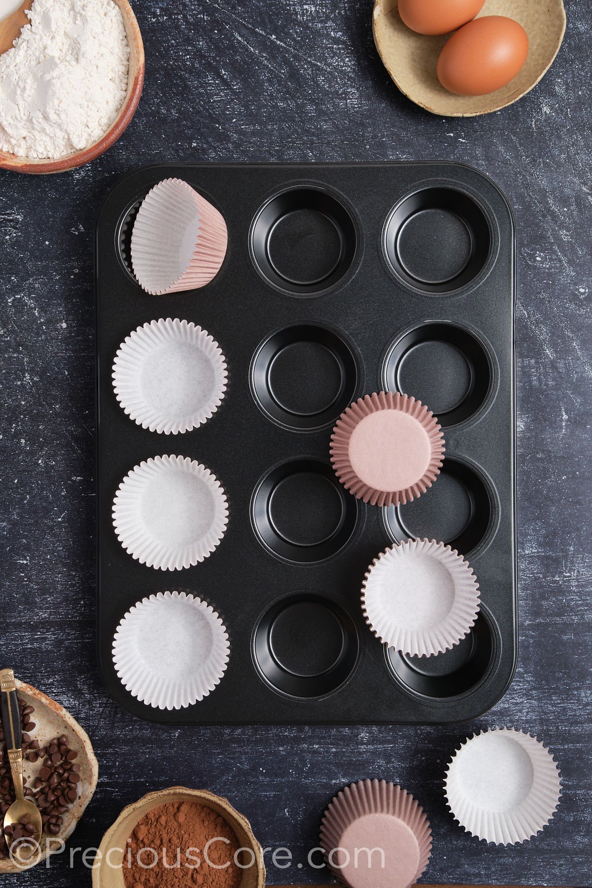 Lining a muffin pan with cupcake liners.