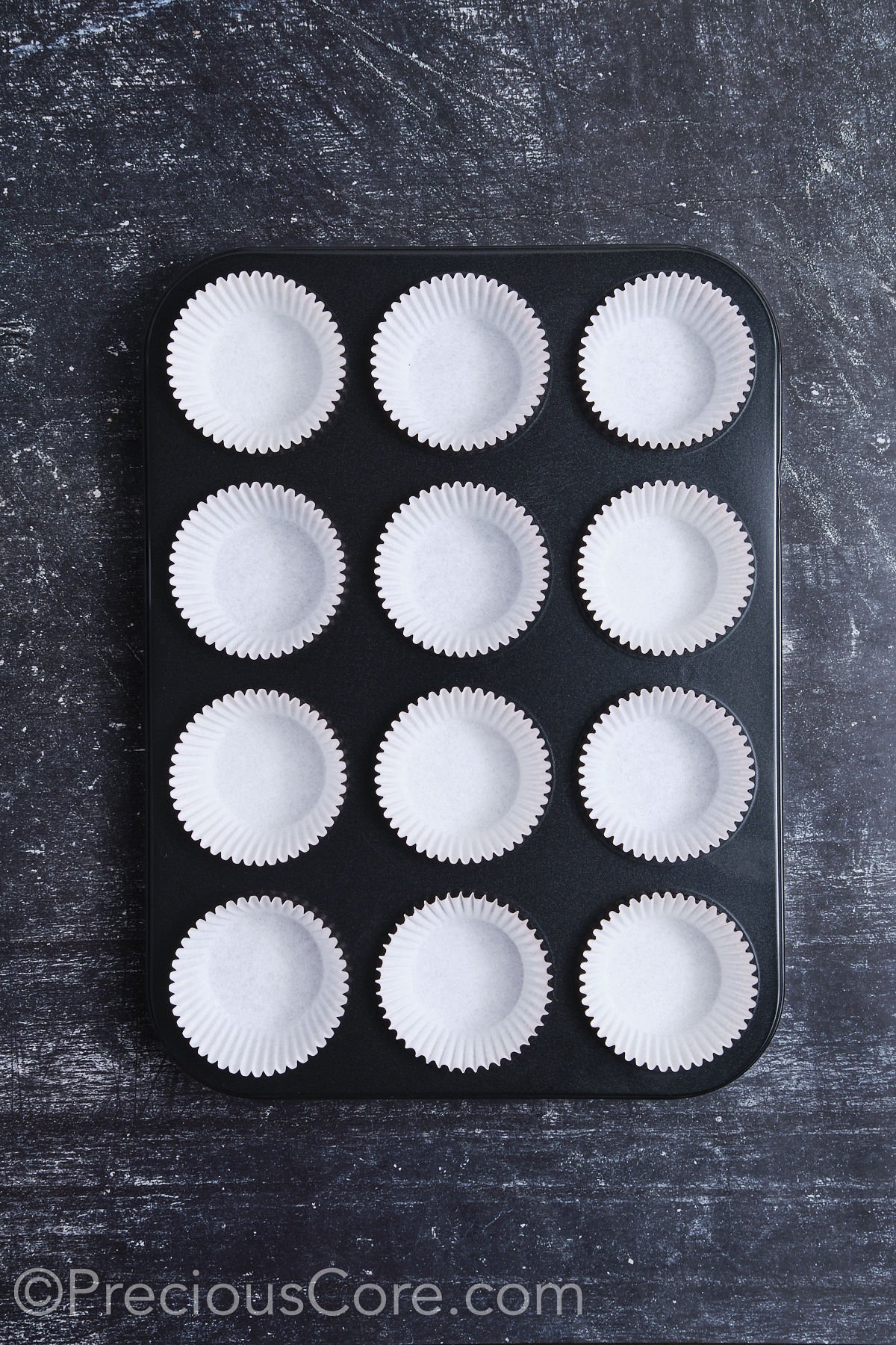 A muffin pan fully lined with cupcake liners.